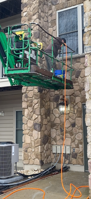 Technician on a lift cleaning a second story dryer vent